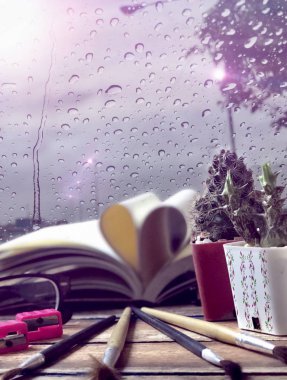 ahşap masa üzerinde defter, gözlük, boya fırçaları ve kaktüsler yakın 