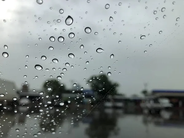 雨の日に市内の交通とぼやけた通りの背景に雨滴と車のフロントガラス — ストック写真