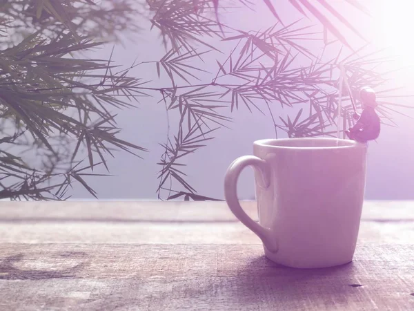 Relaxation in coffee time.Black coffee in white mug,Miniature of fisherman sitting and fishing, relaxed on the cup edge, in Americano coffee,free space for your text, with lens flare, selective focus.