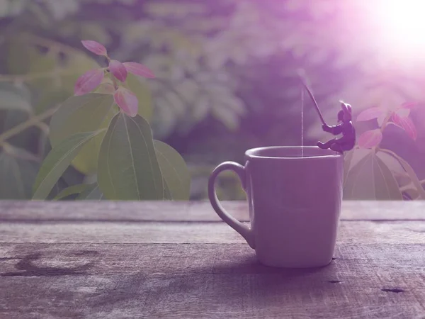 Relaxation in coffee time.Black coffee in white mug,Miniature of fisherman sitting and fishing, relaxed on the cup edge, in Americano coffee,free space for your text, with lens flare, selective focus.