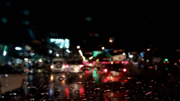 Defocused image,colorful bokeh with street light at night,raindrop on car windshield.Driving car in heavy rain storm.Traffic in the city on a rainy day.