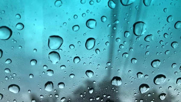 Defocused image, raindrop on car windshield, colorful bokeh with street light at evening.Driving car in heavy rain storm,traffic in the city on a rainy day