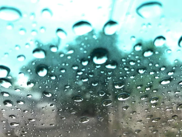 Defocused image, raindrop on car windshield, colorful bokeh with street light at evening.Driving car in heavy rain storm,traffic in the city on a rainy day