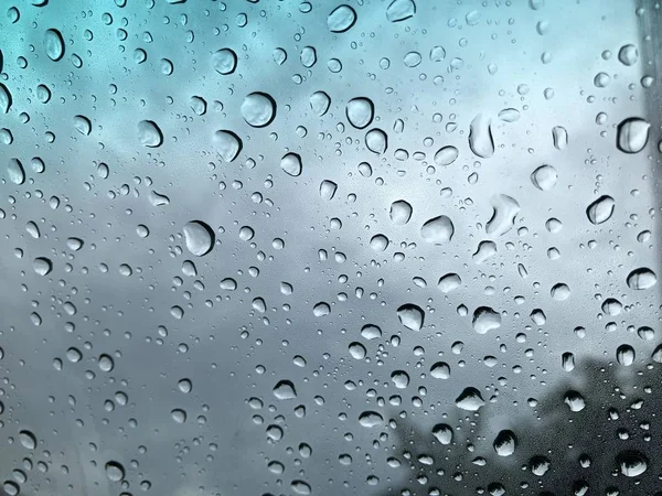 Defocused image, raindrop on car windshield, colorful bokeh with street light at evening.Driving car in heavy rain storm,traffic in the city on a rainy day