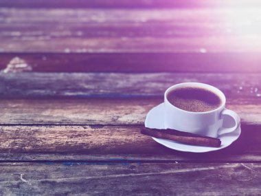 Ahşap masa üstünde bir kupa kahve, sade yaşam, yumuşak koyu ton, loş ışık, lens alevi, metin için boş alan. Kahve zamanı rahatlama kavramı