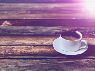 Ahşap masa üstünde bir kupa kahve, sade yaşam, yumuşak koyu ton, loş ışık, lens alevi, metin için boş alan. Kahve zamanı rahatlama kavramı