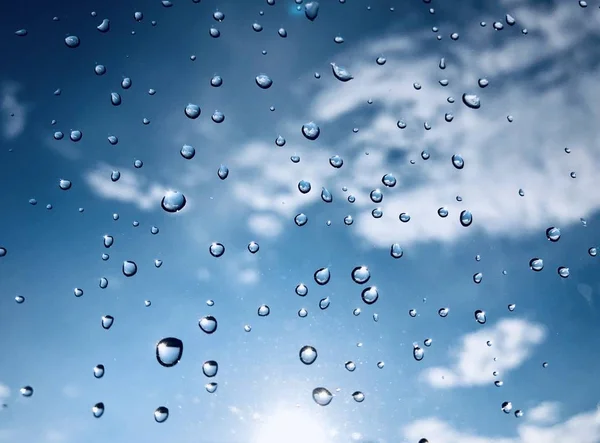 view through window with water drops on cloudy sky