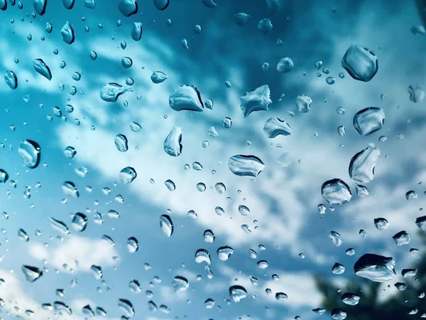 view through window with water drops on cloudy sky