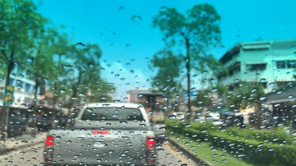 view through window with water drops on car on street