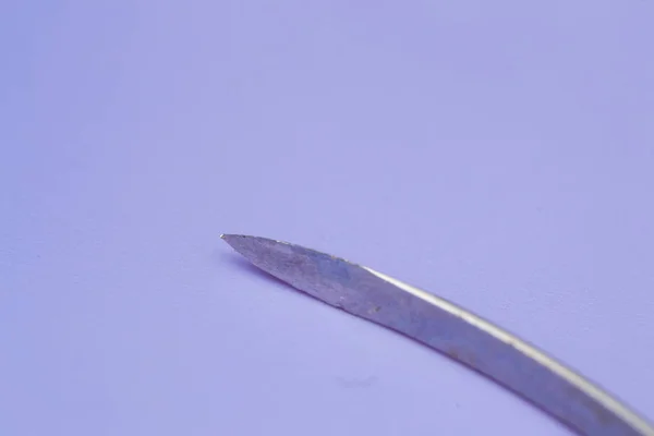 Aguja de corte convencional utilizada en cirugía sobre fondo azul —  Fotos de Stock