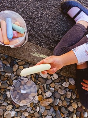 Kız elinde bir parça tebeşir tutuyor.