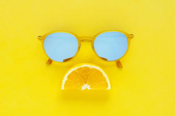 Slice orange fruit set as sad mouth and yellow sunglasses isolated on yellow background for summer time with space for text.