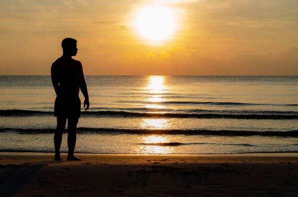 ビーチに一人で立っている男のシルエット写真は、日の出の瞬間を楽しみます — ストック写真