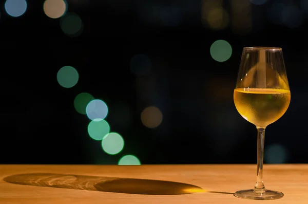 Um copo de vinho branco e sua sombra na mesa de madeira da barra do telhado — Fotografia de Stock