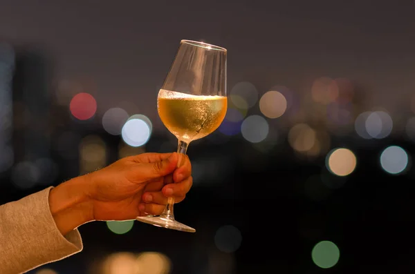 Hand holding a glass of white wine toasting to celebration and party concept