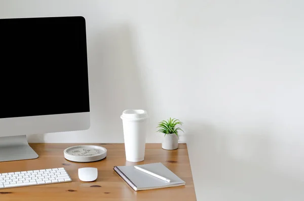 Modern personal computer screen on wooden table with a cup of coffee.