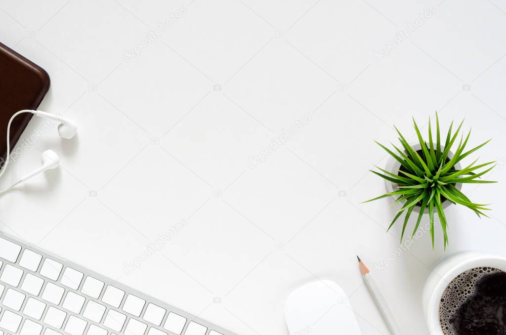 Modern workplace with wireless keyboard and mouse, a cup of coffee, smartphone with earphones, pencil and Tillandsia air plant on white background.