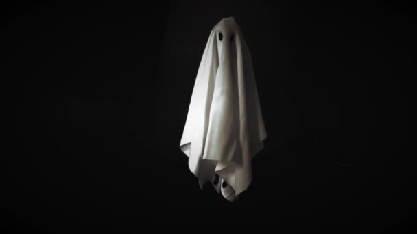 Záběry kostýmů z bílého plechu, které létají vzduchem s černým pozadím. Malý Halloween strašidelný koncept.