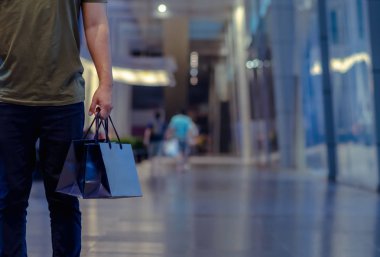 Alışveriş merkezinin arka planında alışveriş torbaları tutan adam. Kara Cuma alışveriş konsepti.