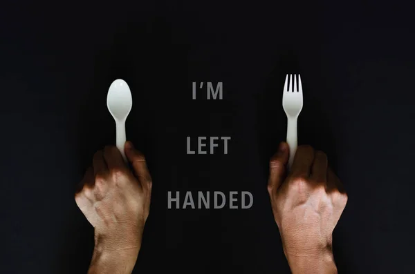 Left handed person holding the spoon on left side with black background for International left handers day concept