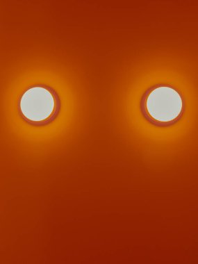 Turuncu duvarda iki beyaz yuvarlak ampul. Arkaplan ve dokulu kavram.