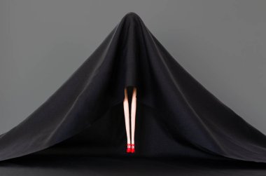 Siyah renkli hayalet kostümlü kız yerden gri arkaplanlı uçuyor. Cadılar Bayramı konsepti.