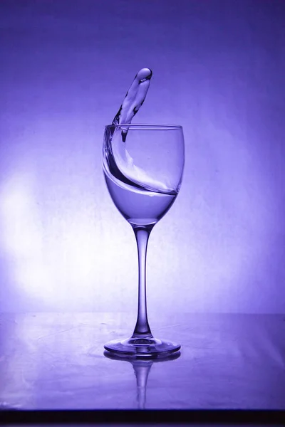 luxury splash drink in a glass on a high leg on a colored background