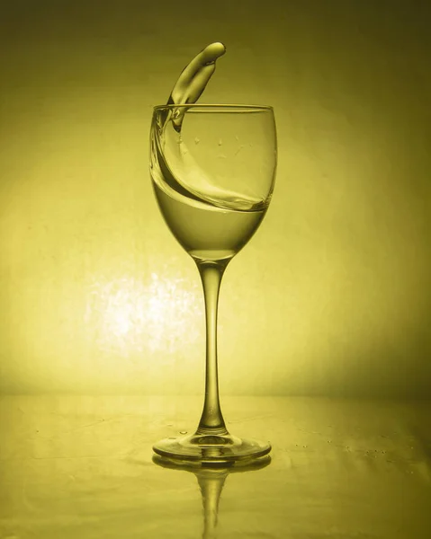 Bebida de lujo salpicadura en un vaso en una pierna alta sobre un fondo de color — Foto de Stock