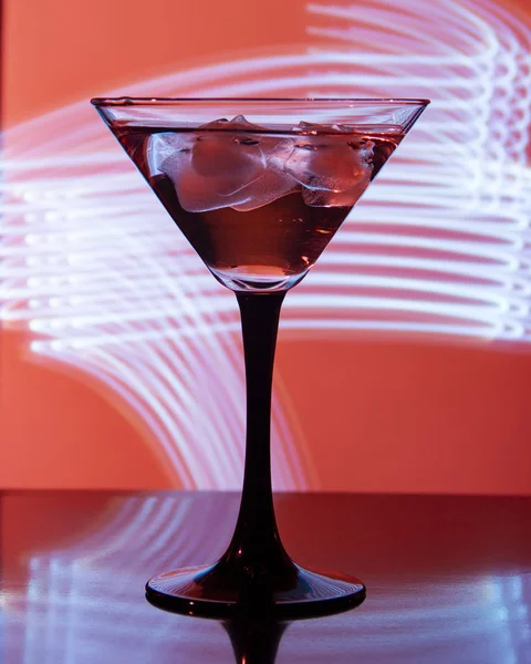 Склянка з коктейлем і льодом на красивому фоні з неоновими плямами — стокове фото
