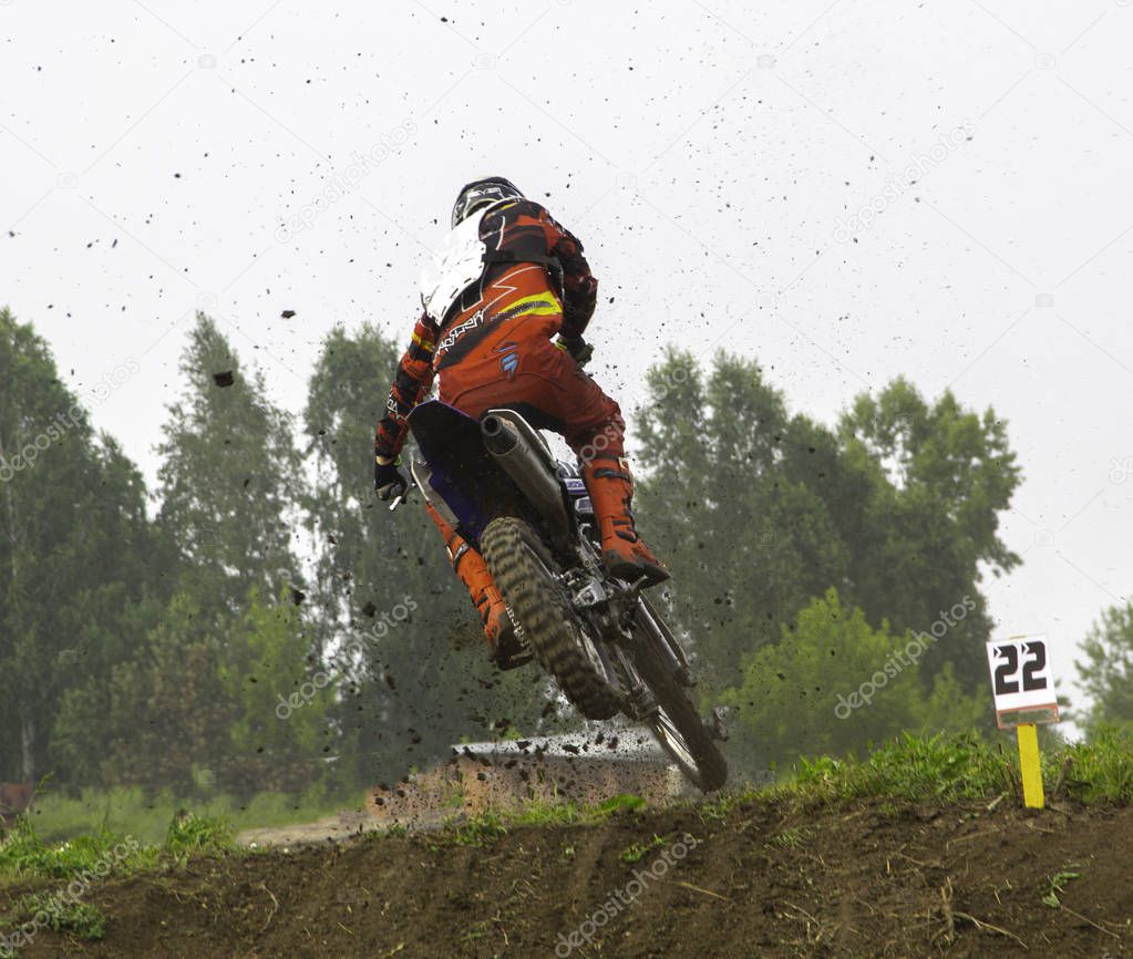 competitionman at motocross competition jumps from a springboard on a motorcycle