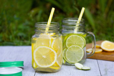 Limon ve limondan oluşan ferahlatıcı bir kokteyl tutacakları ve tüpleri olan moda kavanozlara döküldü.