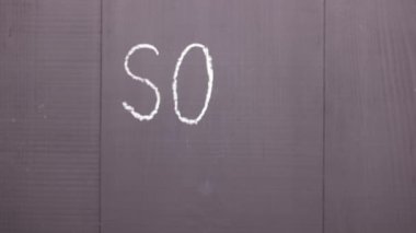 Sos kelimesi siyah tahtaya beyaz tebeşirle yazılmıştır.