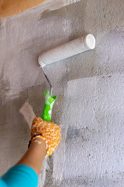 Cement wall painting with white paint and roller. Yellow gloves. — Stock Photo, Image
