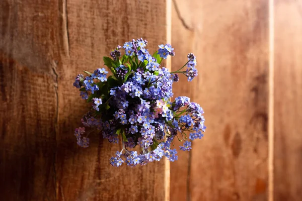 Flores silvestres azules en una taza de vidrio sobre un fondo de madera. No me olvides. . — Foto de Stock