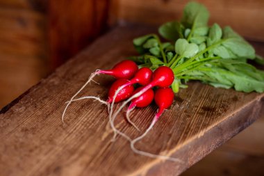 Ahşap bir masada kırmızı turp. Yeşil yapraklı kırmızı sebze.
