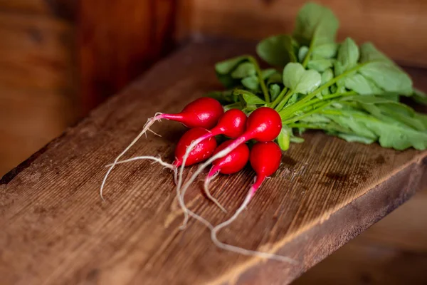 Rábano rojo en una mesa de madera. Vegetales rojos con hojas verdes . — Foto de Stock