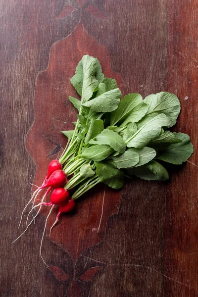 Red radish on a wooden table. Red vegetable with green leaves. — Stock Photo, Image