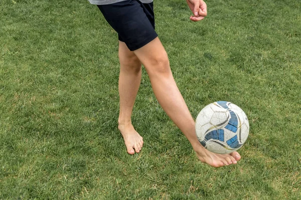 Футболист босиком набивает мяч на зеленой траве . — стоковое фото