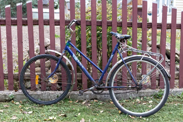 Stary niebieski rower w pobliżu brązowego drewnianego ogrodzenia — Zdjęcie stockowe