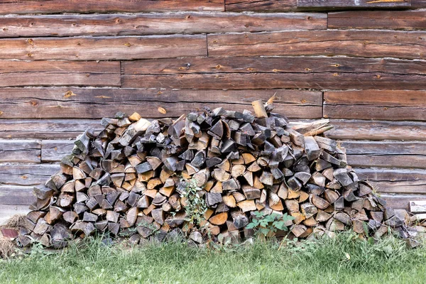Firewood empilhado perto de parede marrom de madeira — Fotografia de Stock