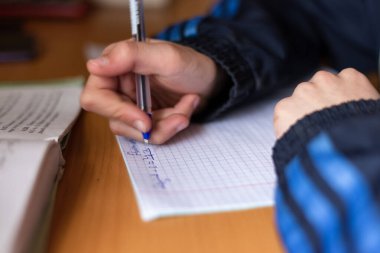 Çocuk bir deftere yazıyor. Çocuk ev ödevi yapıyor. Kalem ve defter. 