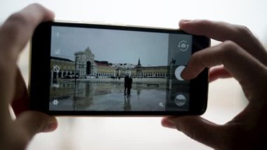 Islak Lizbon 'un fotoğraflarını çeken kadının elleri ve akıllı telefonu.
