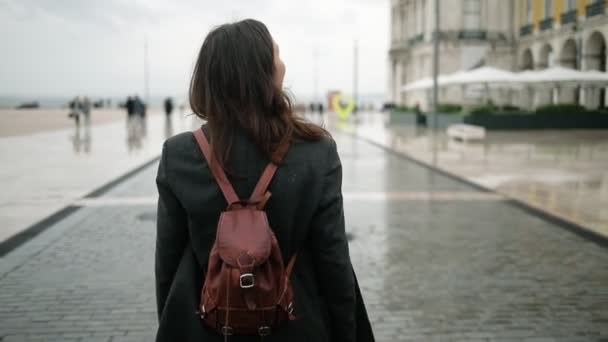 Visão traseira da menina turista bonita vestindo sobretudo e mochila — Vídeo de Stock