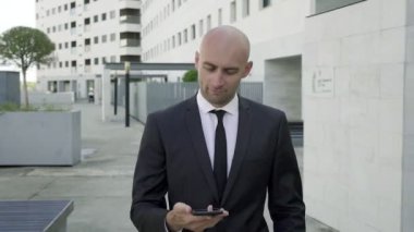 Yakışıklı kel iş adamı akıllı telefonla konuşuyor ve gülümsüyor.