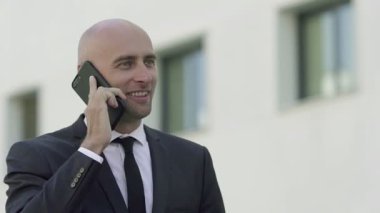 İçerik uzmanı sokakta duruyor ve telefonla konuşuyor.