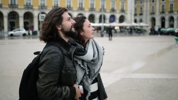 Χαρούμενο νεαρό ζευγάρι τουριστών που αγκαλιάζεται στην πλατεία της πόλης — Αρχείο Βίντεο