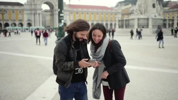 Щаслива пара туристів, які носять пальто, використовуючи додаток місцезнаходження — стокове відео