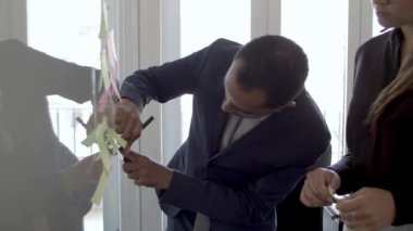 Yapışkan kağıt notlara yazı yazan profesyonel meslektaşlar