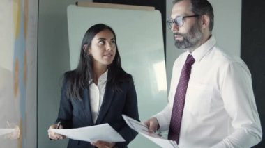 Latin iş kadını elinde belgelerle patronla konuşuyor.