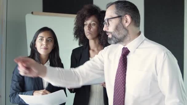 Drei Geschäftspartner halten Dokumente in der Hand und diskutieren das Projekt — Stockvideo